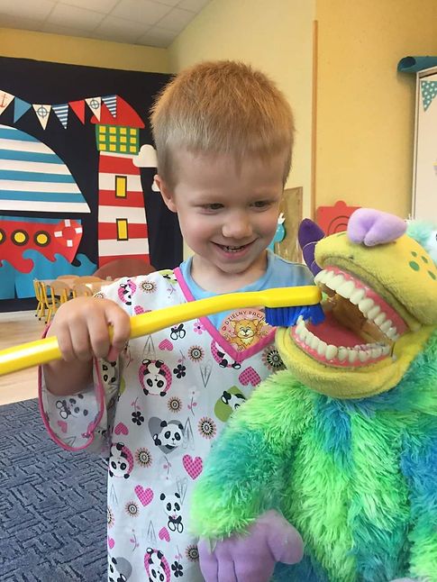 dziecko myje zęby maskotce